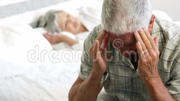 头痛的老人坐在床上视频的预览图