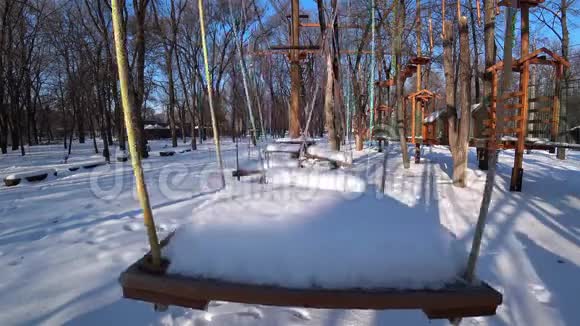 在阳光明媚的冬日空木孩子在城市公园里摇摆视频的预览图