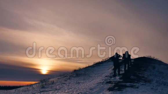 人们冬天剪影雪光一群游客走在夕阳的剪影山上慢视频视频的预览图