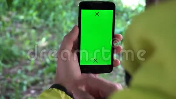 特写男性手握智能手机带有绿色屏幕预设效果视频的预览图