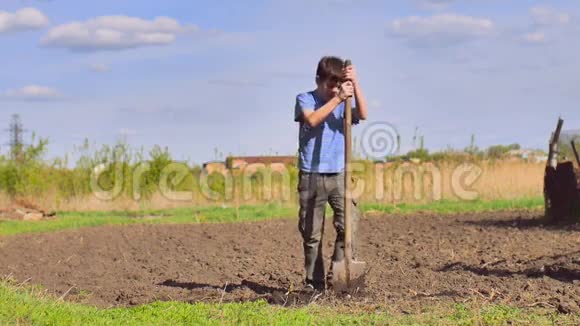 农夫男孩疲倦地挖地旧脏铲干地视频慢动作视频的预览图
