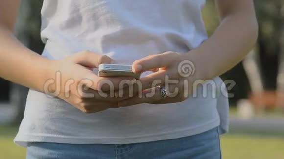在公园里用智能手机应用发短信的女孩视频的预览图