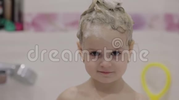 漂亮的三岁女孩洗澡湿发与浴沫可爱的金发孩子棕色的眼睛可爱的女孩微笑视频的预览图