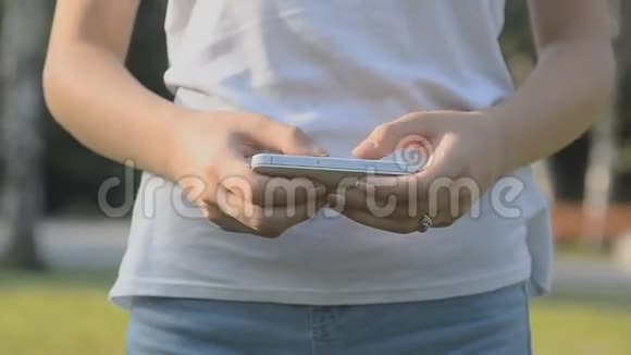 在公园里用智能手机应用发短信的女孩视频的预览图