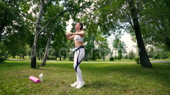女人在户外做健身运动在绿色森林里跑马拉松之前女跑步者伸展身体斯利姆女孩视频的预览图