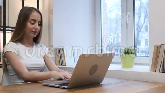 年轻女孩在笔记本电脑上庆祝成功视频的预览图