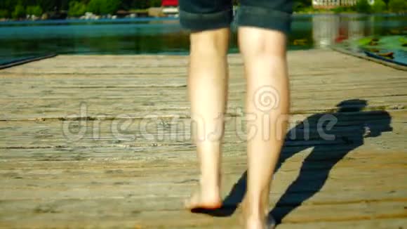 我的赤脚在木墩上穿短裤的女孩走在木墩上视频的预览图