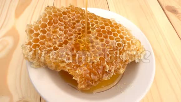 蜂蜜滴在蜂窝上黄色背景慢动作视频的预览图