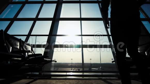 商人在机场使用平板电脑一个带背包的男性旅行者的轮廓商务和旅行视频的预览图