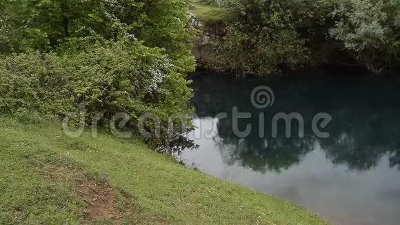 轻松观赏美丽的阿尔巴尼亚大自然绿色植物环绕的天然湖里下着小雨视频的预览图