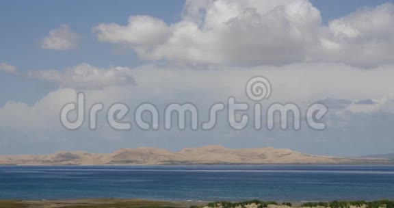 遥远的沙漠沙丘白色蓬松的云团翻滚在蓝色的湖泊上视频的预览图