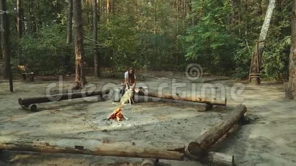 一个女孩坐在森林里看书女孩坐在火旁边的一根木头上读一本书视频的预览图