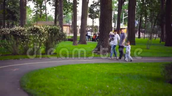 快乐的年轻家庭一起在外面度过绿色的夏日公园视频的预览图