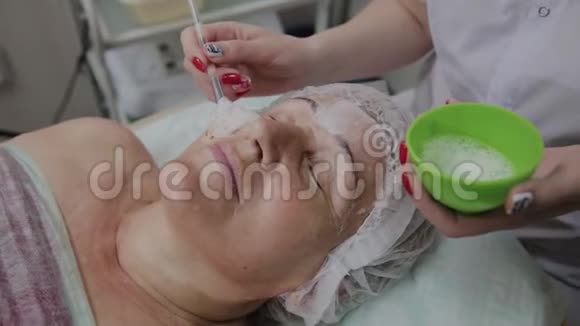 女性美容医生在美容诊所为老年妇女使用面罩视频的预览图
