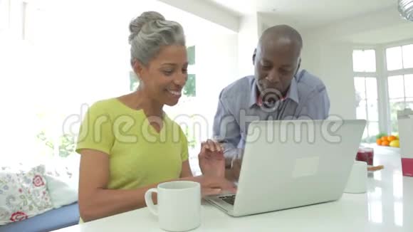 成熟的非裔美国夫妇在家使用笔记本电脑视频的预览图