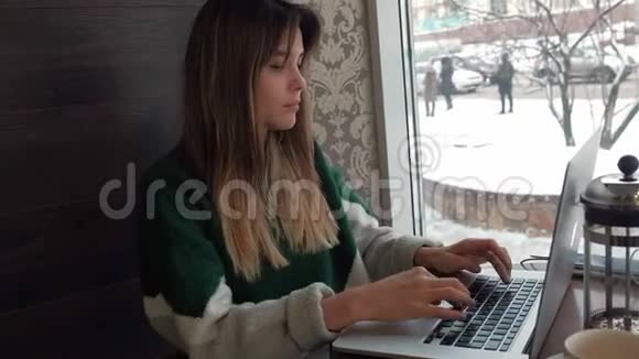 漂亮的女模特坐在咖啡馆的一张桌子上在电脑上工作视频的预览图