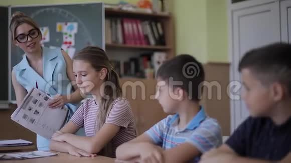 老师在课堂上帮助学校的孩子写作测试教育小学学习和人的概念视频的预览图