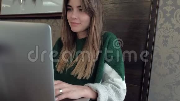 漂亮的女模特坐在咖啡馆的一张桌子上在电脑上工作视频的预览图