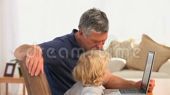 祖父带着孙子看着他们的笔记本电脑视频的预览图