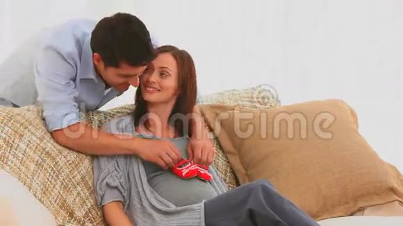 一对夫妇在沙发上玩婴儿鞋视频的预览图