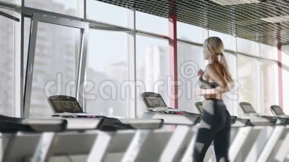 健身女子在健身俱乐部的跑步机上进行有氧运动训练视频的预览图