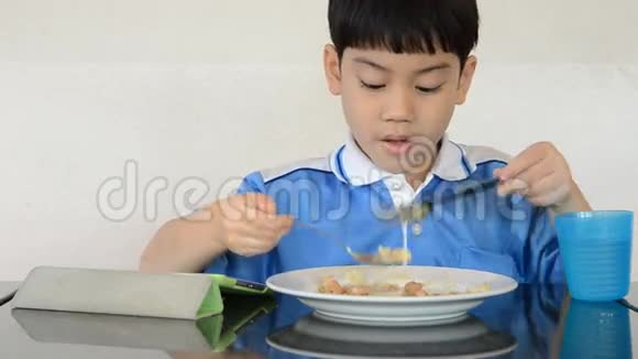 小亚洲男孩吃炒饭玩平板电脑视频的预览图