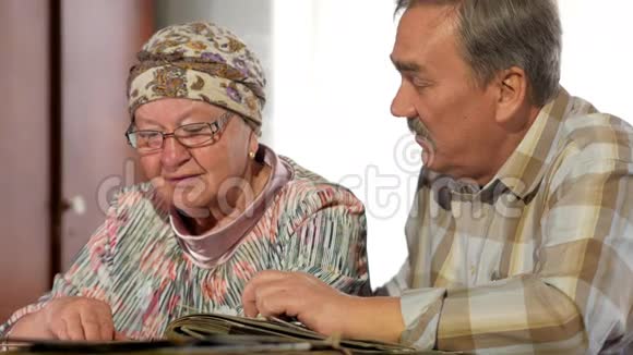 一对老年夫妇正在家里看着他们的旧照片聊天有胡子的男人有老婆的视频的预览图