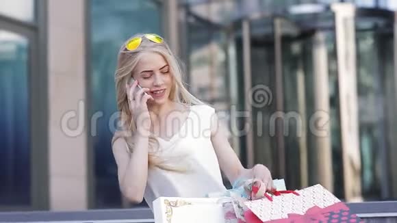 一个女孩在购物后带着漂亮的包裹打电话给她的朋友讲述折扣和销售视频的预览图