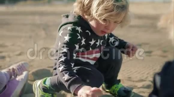 这个男孩正在海滩上玩一辆绿色的玩具自卸卡车视频的预览图