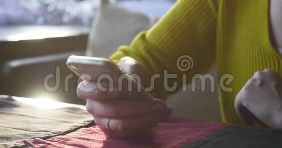 咖啡馆里的女人在等待时使用智能手机视频的预览图