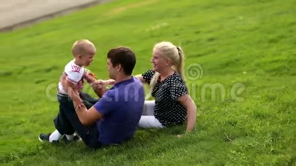 幸福的家庭父亲母亲和小男孩在夕阳的背景下玩耍儿子健康快乐的家庭视频的预览图