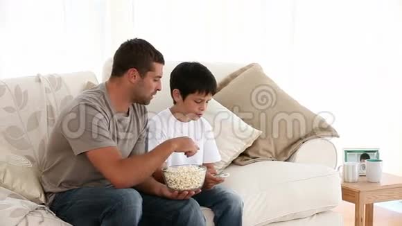 父子俩在沙发上看电视视频的预览图