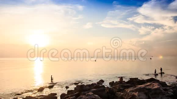 在日落时靠在阳光下的岩石在海上剪影视频的预览图