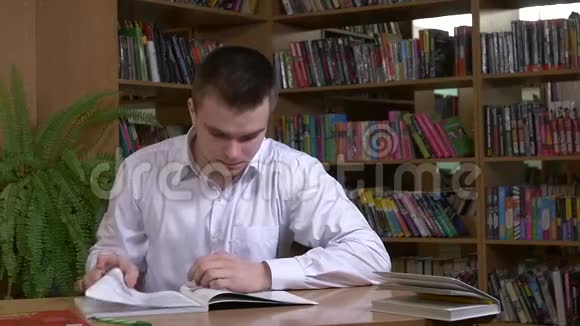 在图书馆里用书做研究的男学生视频的预览图