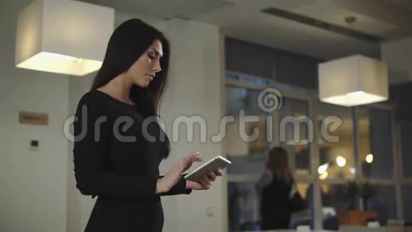 女商人站在办公室拿着平板电脑说话视频的预览图
