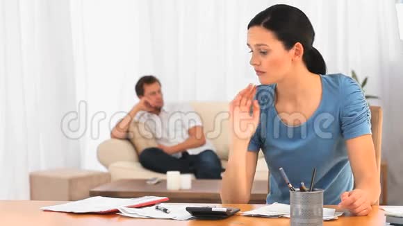 丈夫在沙发上时美丽的女人看着她的账单视频的预览图
