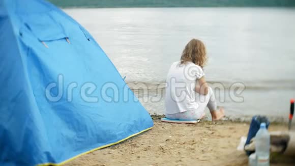 一个女人在营地里用水壶吃饭背景是一个帐篷视频的预览图
