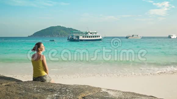 年轻的女人坐在海滩上看着船泰国西米兰群岛视频的预览图