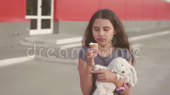 吃冰淇淋的小女孩走在街上有一个柔软的玩具动作慢动作视频女孩和冰淇淋生活方式视频的预览图