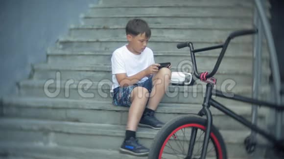 这个男孩坐在梯子上戴着虚拟眼镜旁边是自行车BMX视频的预览图