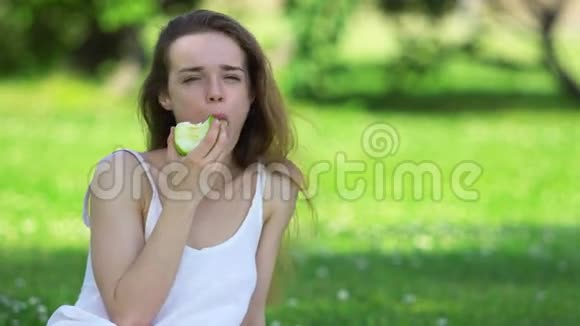 年轻女子咬着美味的绿苹果视频的预览图