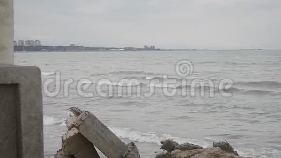 海浪拍打着岩石里海的海浪拍打着海滩上的一座岩石和古老的金属建筑视频的预览图