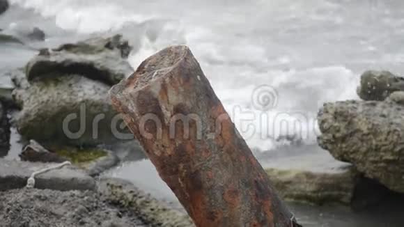 海浪拍打着岩石里海的海浪拍打着海滩上的一座岩石和古老的金属建筑视频的预览图
