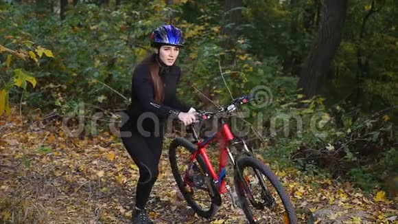 一位年轻女子骑着自行车在秋天的公园里散步视频的预览图