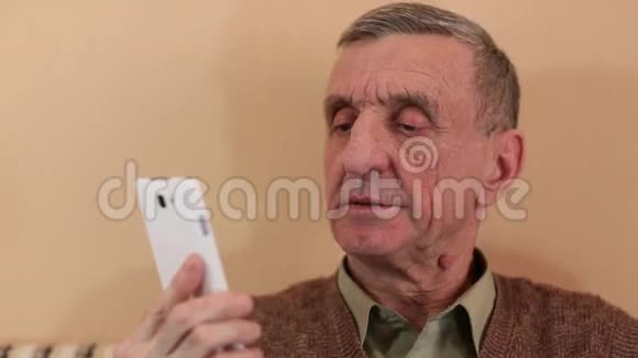 戴着白色智能手机的老人说话微笑视频的预览图