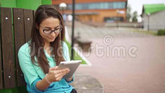 优雅的年轻女孩使用迷你平板戴眼镜的漂亮学生视频的预览图