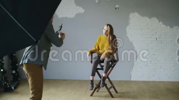 年轻漂亮的女模特在室内照相馆用数码相机拍照时为摄影师摆姿势视频的预览图