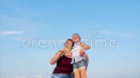 快乐的奶奶带着孩子玩着放风筝一家人在热带海洋的沙滩上玩耍视频的预览图