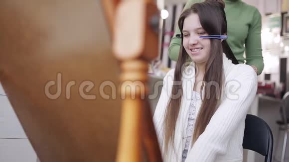 专业的发型师卷起少女的头发视频的预览图