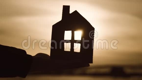 剪影手与纸屋在日落背景视频的预览图